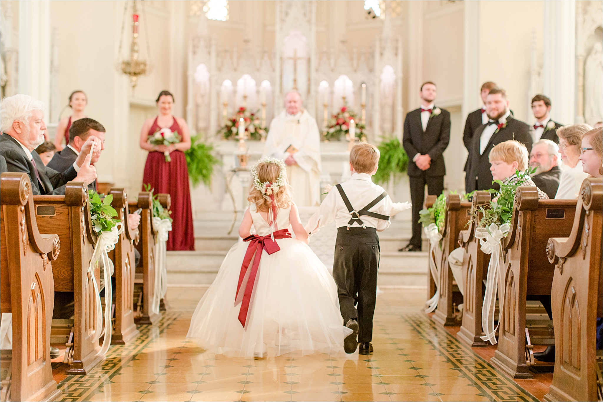flower-girl-ring-bearer-holding-hands-walking-down-aisle-cranberry-wedding-colors-full-skirt