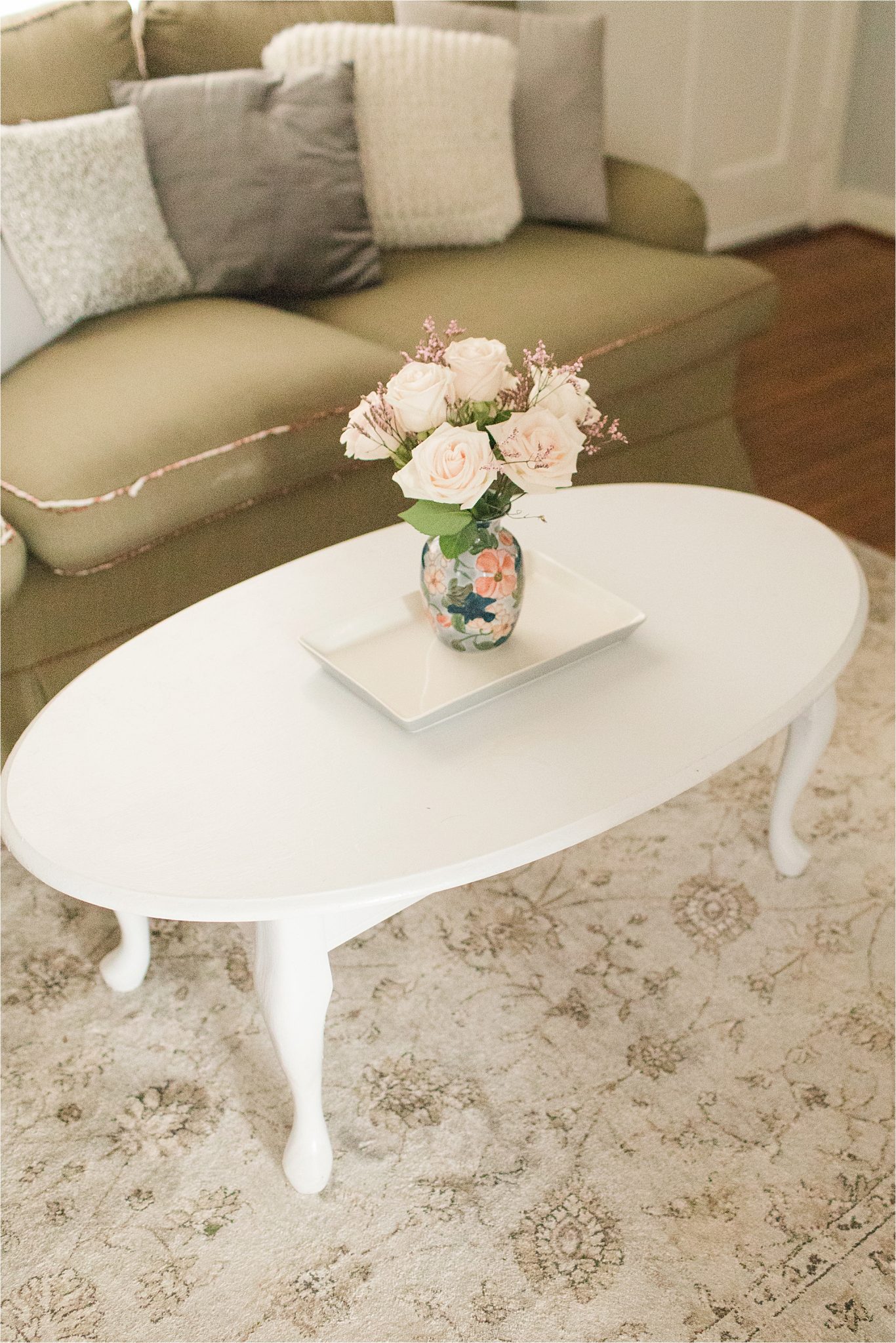 first-home-living-room-vintage-airy-neutrals-family-photos-white-coffee-table-fresh-flowers