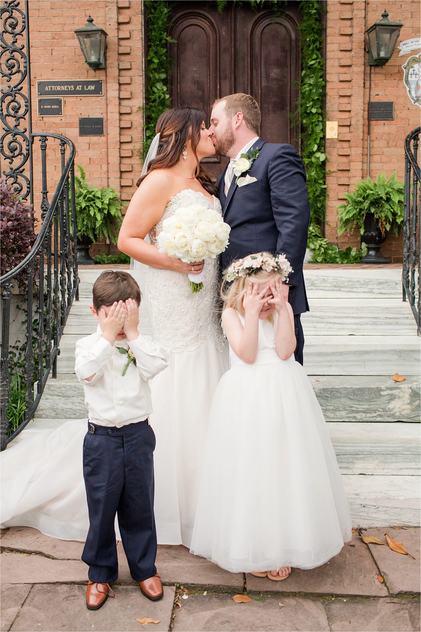 cute ring bearer and flower girl pics-with the bride and groom-flower crown flower girl-eyes covered-kissing